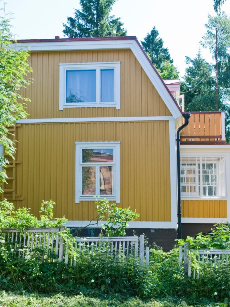 traditional yellow wooden house surrounded by trees