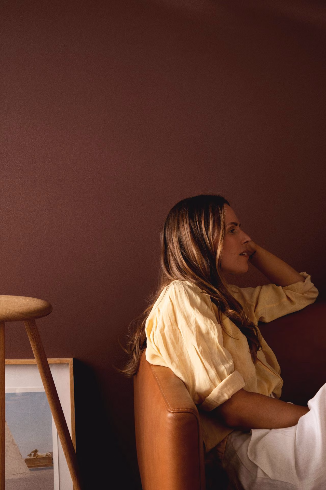 woman sitting on sofa in front of warm brown colour wall
